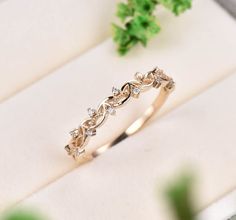 a gold ring with diamonds on it sitting next to some leaves and greenery in the background