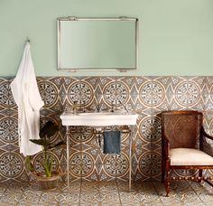 a white sink sitting under a mirror next to a wooden chair and potted plant