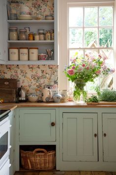 a kitchen filled with lots of green cupboards and white cabinets next to a window