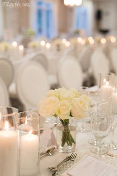 the table is set with white flowers and candles for an elegant wedding reception or special event