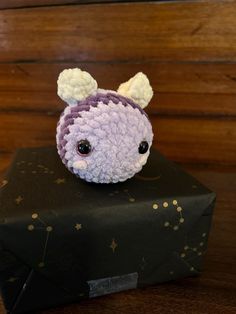 a crocheted animal sitting on top of a black box with stars around it