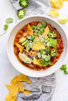 a white bowl filled with chili and tortilla chips on top of a table