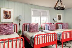 three red beds in a room with white walls and rugs on the floor next to each other