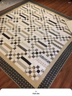 a black and white quilt sitting on top of a wooden floor next to a rug