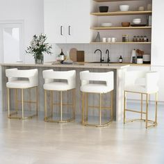 three white bar stools sitting in front of a kitchen island