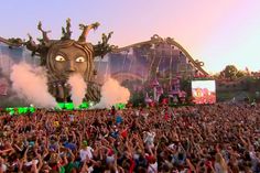 a large group of people standing in front of a stage with an animal face on it