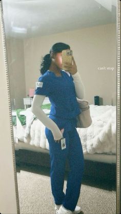 a woman in scrubs taking a selfie in front of a mirror with her cell phone