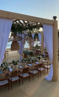 an outdoor wedding setup with white draping and flowers on the tables at sunset