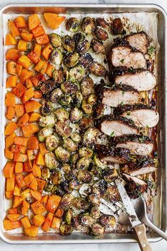 an assortment of roasted vegetables and meat on a baking sheet with a serving utensil