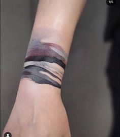 a person with a wrist tattoo that has different colored strips on it and is holding their hand