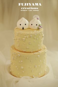 two small white birds sitting on top of a yellow tiered wedding cake with bubbles