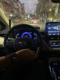 a man is driving his car on the street at night with an electronic display in front of him