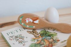 a wooden spoon sitting on top of a book next to an egg