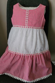 Pink gingham and white eyelet 100% cotton fabrics. Two tiers ruffle skirt. Insertion trim with pink ribbon connect bodice and skirt and the tiers. Lace trim in hem. Cute Cotton Tiered Dress, Cute Cotton Dress With Tiered Skirt, Gingham Tiered Dress For Picnic, White Ruffle Hem Dress For Picnic, Plaid Cotton Tiered Dress, Picnic Gingham Dress With Lace Trim, Cotton Lace Trim Dress For Picnic, Gingham Tiered Ruffle Dress, Gingham Tiered Dress With Ruffles