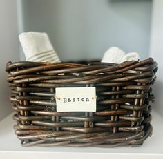 a wicker basket sitting on top of a white shelf next to a towel rack