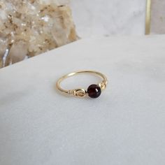 * Garnet Round Gemstone Bead, 4mm * 14/20 gold-filled (5%) with jeweler's brass core, 1.6 mm round wire * Refer to the ring size guide in the photos above for a perfect fit. * Arrives beautifully packaged, ideal for gifting yourself or a loved one. * Easy care instructions in the photos above that ensure long-lasting beauty. * A jewelry care card and cleaning cloth are included. Adorn your style effortlessly with a handcrafted wire wrapped ring. This piece of jewelry combines the enduring allure Minimalist 14k Gold Wire Wrapped Rings, Minimalist Gold Birthstone Ring With Gemstone, Minimalist Amber Ring Jewelry, Minimalist Adjustable Gold Birthstone Ring, Minimalist Amber Birthstone Jewelry, Minimalist Wire Wrapped Yellow Gold Ring, Handmade Dainty 14k Gold Birthstone Ring, Handmade Minimalist Gold Birthstone Ring, Gold Minimalist Handmade Birthstone Ring