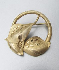 This very pretty 1940s late Art Deco period brooch is signed BB for Binder Brothers and 12k GF for gold filled.  It is a circle design with three textured overlaid leaves.  It measures 1.25 inches across and is in excellent condition with no signs of any wear or damage.    FREE SHIPPING within the USA and it will arrive gift boxed.    072 Art Deco Yellow Gold Collectible Brooches, Mid-century Yellow Gold Brooch For Gifts, Gold Art Deco Brooches For Anniversary, Mid-century Yellow Gold Brooch Jewelry, Mid-century Yellow Gold Brooch, Gold Art Deco Anniversary Brooches, Gold Art Nouveau Brooch For Collectors, Engraved Round Gold Brooches, Gold Round Engraved Brooches