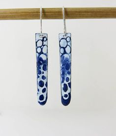 blue and white earrings hanging from a wooden hook