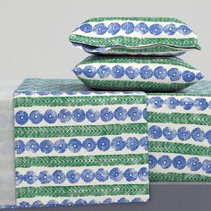 three pillows stacked on top of each other with blue and green designs in the middle