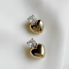 Elevate any outfit with The Scarlette Studs, featuring a puffed heart design adorned with a sparkling touch of cubic zirconia. Perfect for adding a touch of elegance and charm to any look. 18k Gold-Plated Brass Cubic Zirconia Post back closure Drop 15mm Jewelry Care: Clean metal jewelry with a soft cloth and mild soapy water. Avoid abrasive cleaners, steamers, or ultrasonic machines. Dry thoroughly and store dry place. Valentine's Day Gold Jewelry With Sparkling Stones, Gold Bling Heart Pendant Jewelry, Gold Heart Pendant Jewelry With Bling, Elegant Heart-shaped Bling Jewelry, Gold Cubic Zirconia Heart Earrings For Party, Glamorous Gold Heart Earrings, Gold Heart-shaped Cubic Zirconia Earrings, Elegant Gold Plated Heart Earrings For Wedding, Gold Double Heart Earrings For Formal Occasions