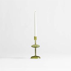 a white candle sitting on top of a green stand