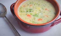 a red bowl filled with soup next to a spoon