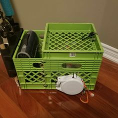 a green crate sitting on top of a wooden floor next to a blow dryer