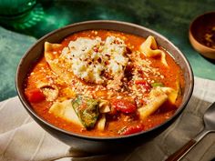 a bowl filled with pasta and sauce on top of a napkin next to a spoon