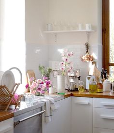 a kitchen filled with lots of white appliances and flowers on top of the counter tops