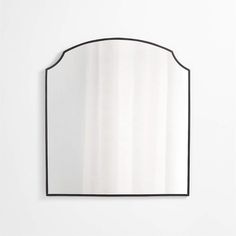 a mirror that is on the wall in front of a white wall with a black frame