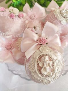 some pink and white ornaments with bows on them are sitting on a table next to flowers