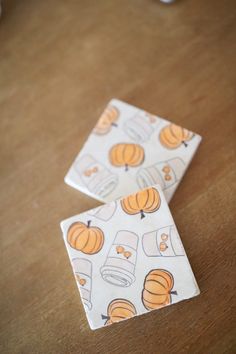 two pieces of paper with pumpkins on them sitting on a table next to cups