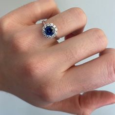 a woman's hand with a blue and white diamond ring on top of it