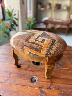 a wooden table with a foot stool on it's legs and a plant in the background