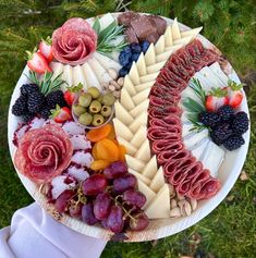 a platter filled with different types of cheeses and meats on top of each other