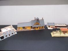 three model houses are sitting on a black counter top, one is yellow and the other is blue