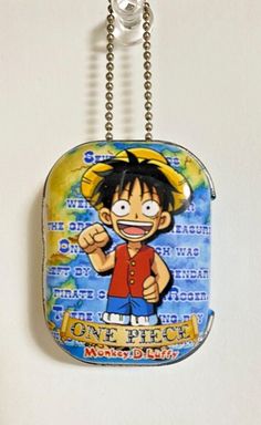 one piece keychain hanging from a chain on a white wall with an image of the character