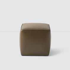 a small square stool with a leather seat cover on it's back end, in front of a white background