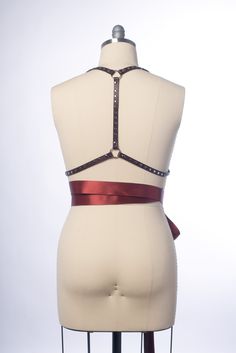 High quality, durable-yet-delicate bespoke harness made in leather or PVC. Embellished with studs along straps. Luxurious wide satin ribbons wrap around the waist and tie into a bow. Silver-toned nickel plated steel hardware. Shown in natural tan leather and oxblood leather. All colors have matching ribbon ties (clear has black ribbon). Also available in PVC and vegan leather. Custom sizing available. All pieces are MADE TO ORDER, standard sizes XS-4XL. If your measurements fall outside these st Adjustable Belt Harness For Party, Adjustable Strap Harness For Party, Adjustable Straps Harness For Party, Adjustable Strapped Harness For Party, Fitted Strapped Harness For Party, Adjustable Strapped Party Harness, Adjustable Party Harness, Party Satin Corset Belt, Adjustable Leather Corset Belt For Party