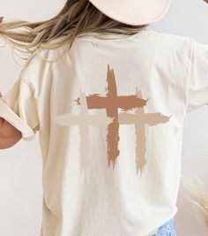 This unisex Boho Christian t-shirt features a beautiful design that showcases  3 veritical overlapped crosses in neutral colors and minimalist graphic design. With a soft and comfortable fabric, this tee is perfect for casual wear, whether you're at church, a Christian concert, shopping or sipping your favorite beverage and just while hanging with your friends. Rolled sleeves in picture is for styling purposes only. Printed on Cotton Bella and Canvas and Comfort Colors T-shirts (see colors in listing).  Make it an Oversized Tee for a current trendy look! Boho Christian Shirts Christian t shirts Jesus Shirt Love Like Jesus Christian Apparel Jesus Apparel Christian Crewneck Bible Verse Shirt Great Gift for Birthday or any occasion. Perfect for the gym, working out, hanging with friends or te Tshirt Design Christian Faith, Christian Tshirt Design Ideas Minimalist, Church Shirts Design, Christian T Shirt Designs Graphics, Cute Christian T Shirts, Church Shirts Ideas, Trending Tshirt Design Ideas, Christian Graphic Tees Design