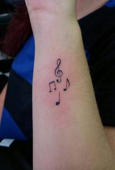 a wrist tattoo with musical notes on it