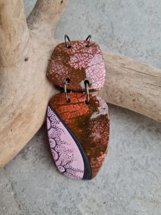 two brown and pink earrings sitting on top of a tree branch