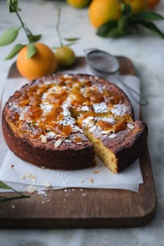 a cake is sitting on a cutting board next to some oranges