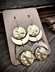 four silver and gold earrings on top of a piece of wood