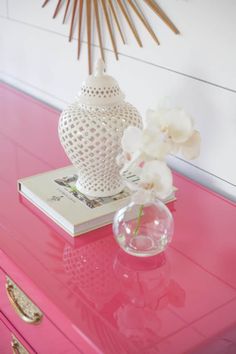 a white vase sitting on top of a pink dresser