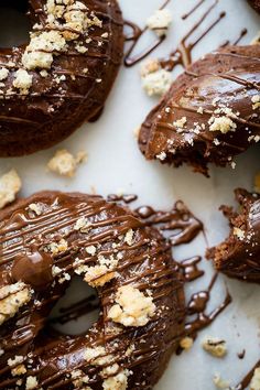 chocolate covered doughnuts are on a white surface with crumbled toppings