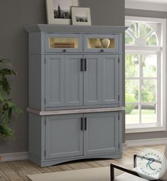 a gray cabinet with two doors and drawers in a living room next to a window