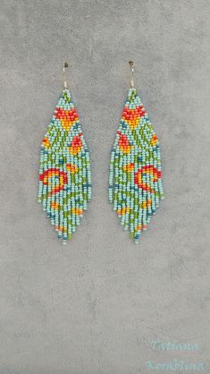 two pairs of beaded earrings are shown on a gray surface, one is green and the other is orange