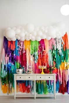 the room is decorated with many different colored streamers and white balloons hanging from the ceiling