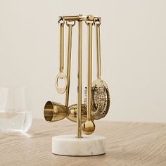 a golden clock on top of a white marble base next to a glass of water